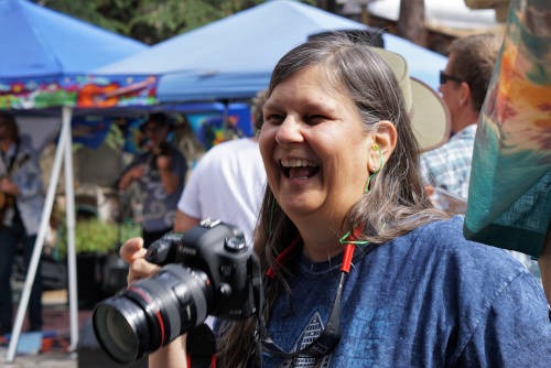 Susan laughing with her camera at an outdoor festival